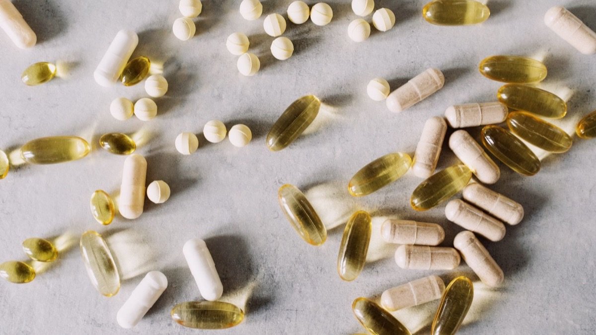 Assorted vitamin and supplement capsules and tablets on a stone surface